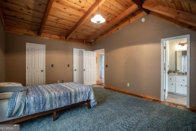 bedroom with connected bathroom, vaulted ceiling with beams, baseboards, wooden ceiling, and wood finished floors