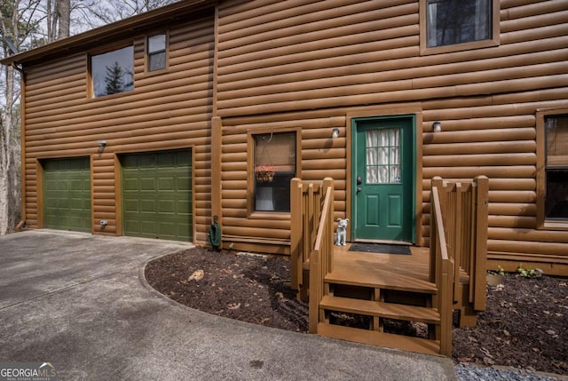 entrance to property featuring log veneer siding, a garage, and driveway