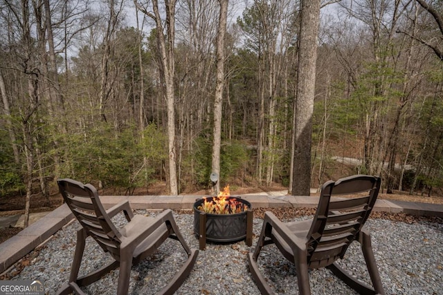 view of patio / terrace with an outdoor fire pit and a forest view