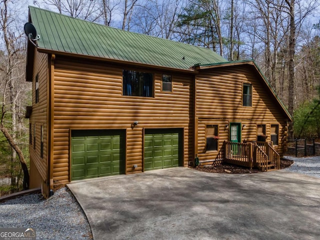 view of front facade featuring driveway, metal roof, and a garage