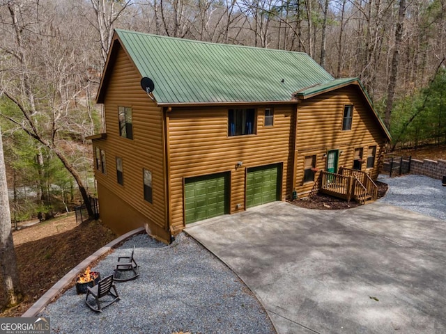 exterior space featuring an attached garage, metal roof, and driveway