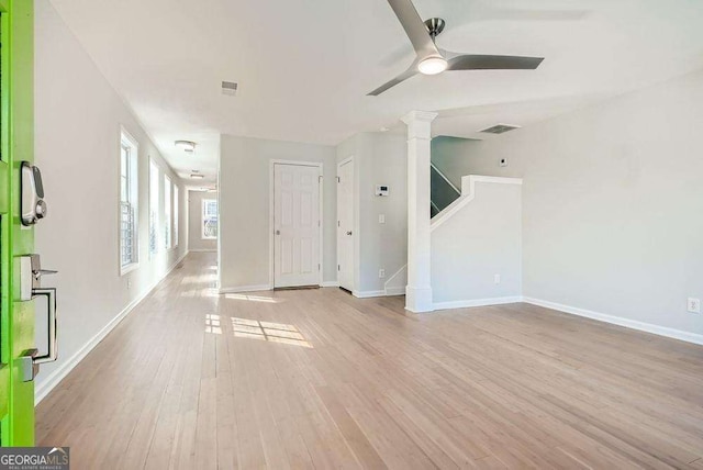 unfurnished living room featuring ceiling fan, light wood-type flooring, baseboards, and stairs