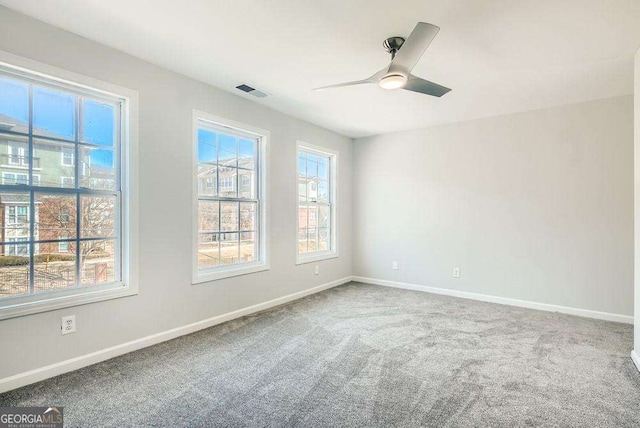 spare room featuring baseboards, a ceiling fan, carpet, and a wealth of natural light
