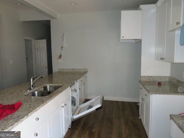 kitchen with light stone countertops, dark wood-type flooring, a peninsula, and a sink