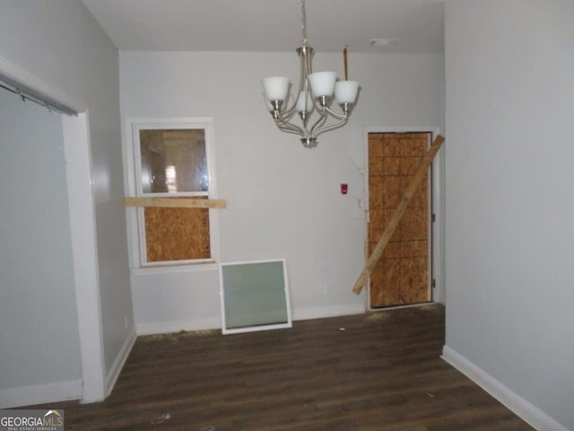 unfurnished dining area with an inviting chandelier, wood finished floors, and baseboards