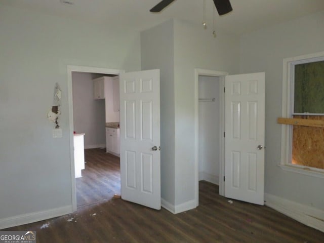 unfurnished bedroom with a walk in closet, wood finished floors, baseboards, and a ceiling fan