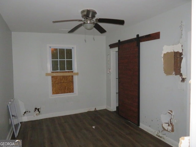 spare room with wood finished floors, radiator heating unit, a barn door, baseboards, and ceiling fan