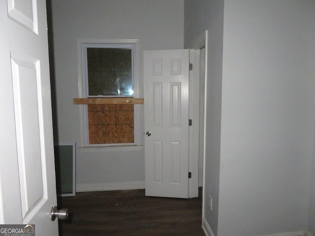 hallway featuring dark wood finished floors and baseboards