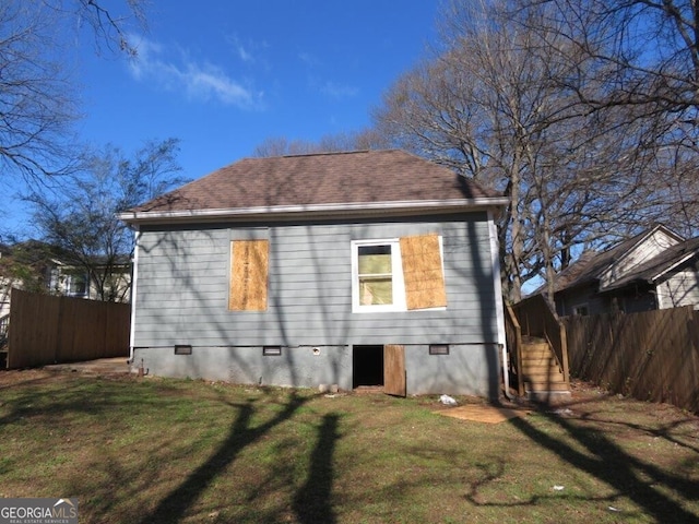 view of home's exterior with crawl space, a shingled roof, a yard, and fence