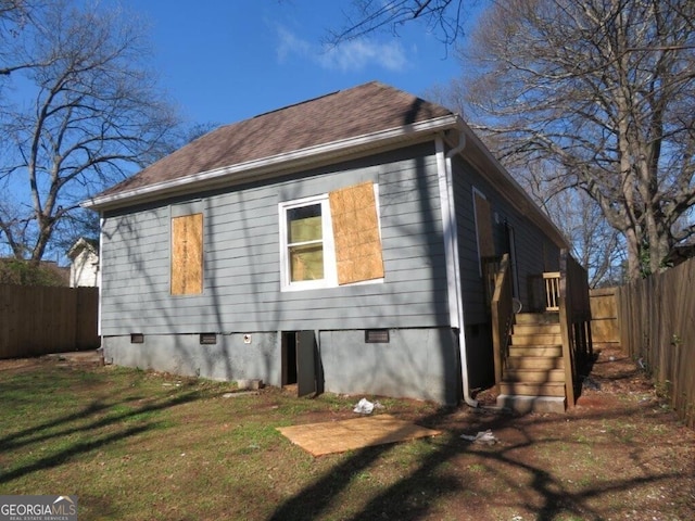 view of home's exterior featuring crawl space, a yard, a shingled roof, and fence