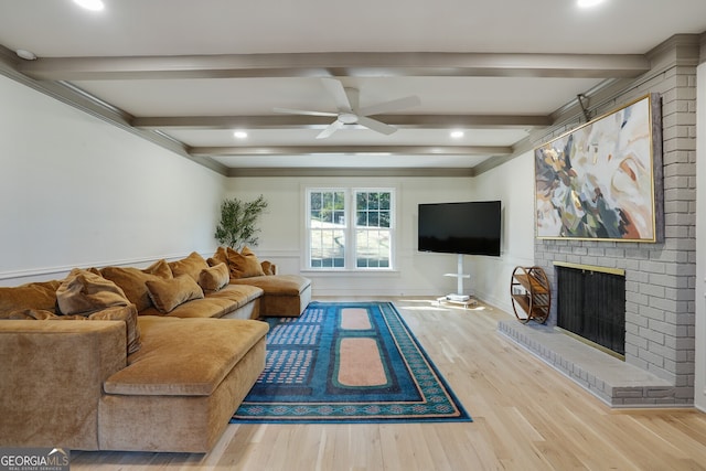 living room with ceiling fan, beamed ceiling, wood finished floors, and a fireplace