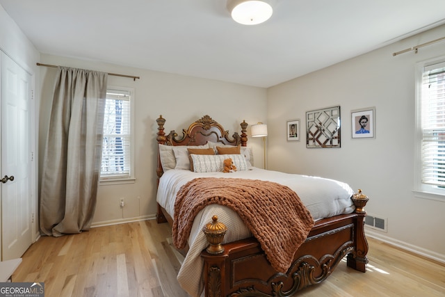 bedroom featuring baseboards, light wood-type flooring, multiple windows, and visible vents