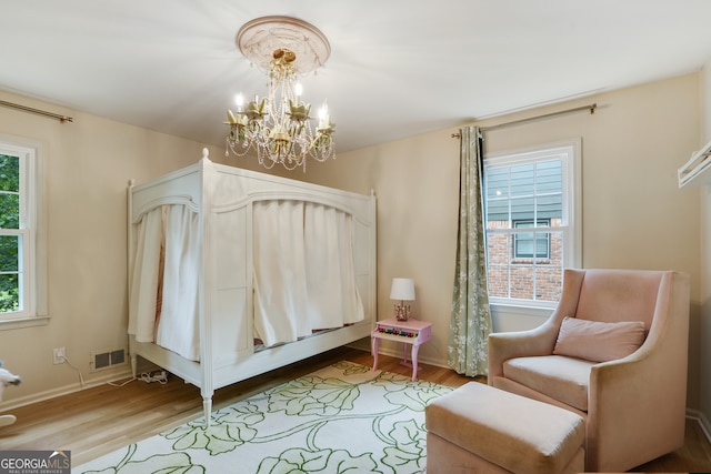 bedroom featuring visible vents, an inviting chandelier, baseboards, and wood finished floors