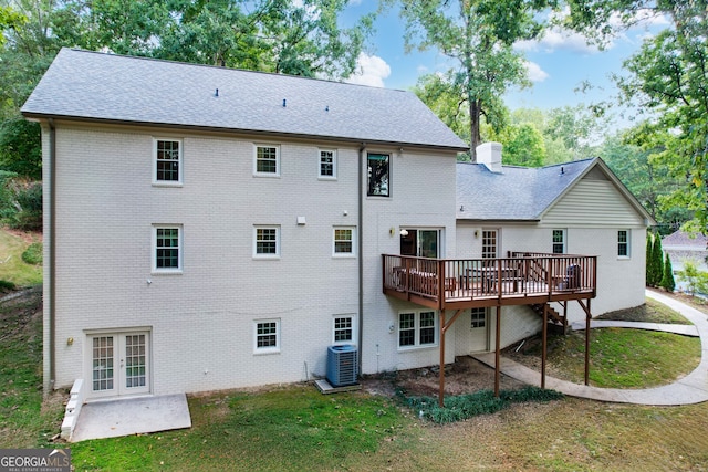 back of property with brick siding, french doors, a chimney, and central AC