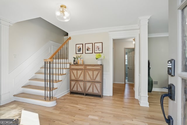 staircase with baseboards, wood finished floors, crown molding, and ornate columns