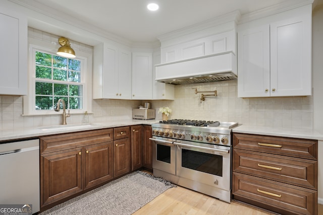 kitchen with white cabinetry, range with two ovens, a sink, light countertops, and dishwasher