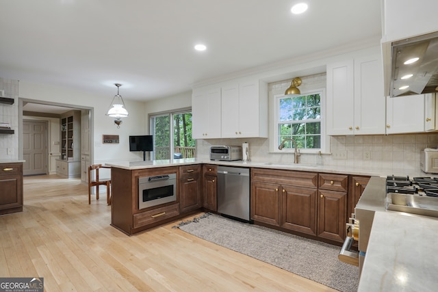 kitchen featuring light wood-style flooring, appliances with stainless steel finishes, light countertops, and a sink