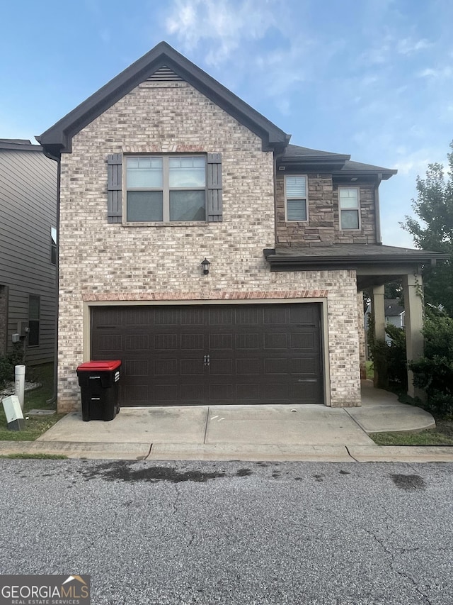 view of front of property featuring stone siding, brick siding, a garage, and driveway