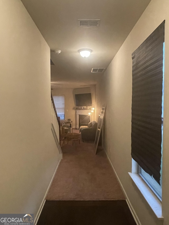 hall with baseboards, visible vents, and carpet flooring
