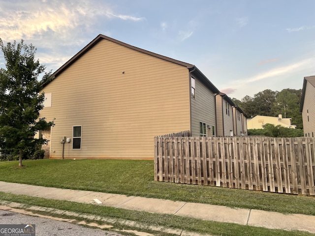 view of side of property with a lawn and fence