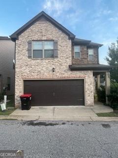 view of front of property featuring driveway, stone siding, and an attached garage