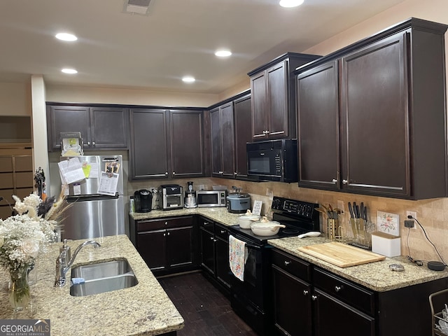kitchen with tasteful backsplash, dark wood-style flooring, a sink, visible vents, and black appliances