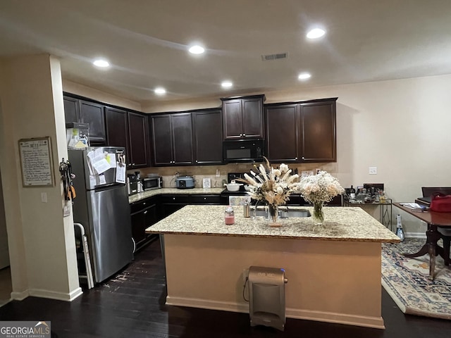 kitchen with visible vents, a kitchen island with sink, stainless steel appliances, recessed lighting, and light stone counters