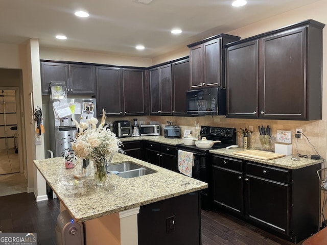 kitchen featuring a center island with sink, light stone countertops, dark wood-type flooring, and black appliances