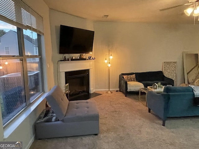living area with a ceiling fan, carpet, a fireplace with flush hearth, and baseboards