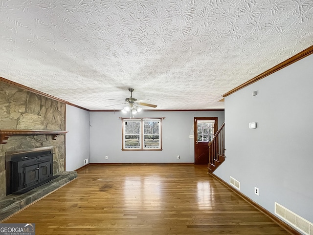 unfurnished living room featuring visible vents, baseboards, wood finished floors, and stairs