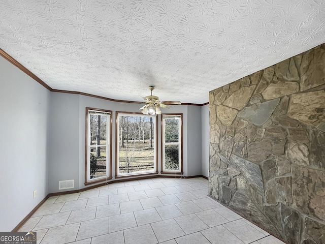 spare room featuring a ceiling fan, visible vents, baseboards, tile patterned flooring, and crown molding