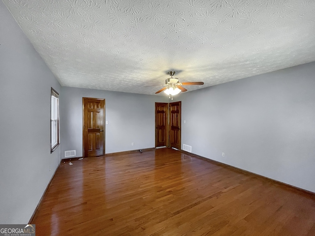 spare room with baseboards, wood finished floors, visible vents, and ceiling fan