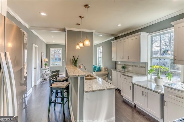 kitchen with tasteful backsplash, dark wood finished floors, white cabinetry, freestanding refrigerator, and hanging light fixtures