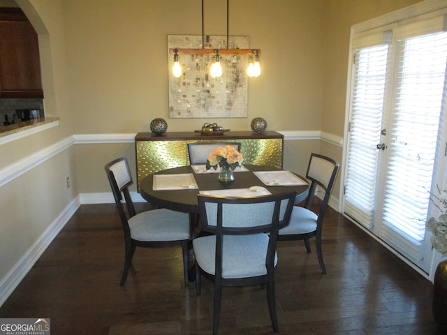 dining space featuring baseboards, dark wood-type flooring, and arched walkways