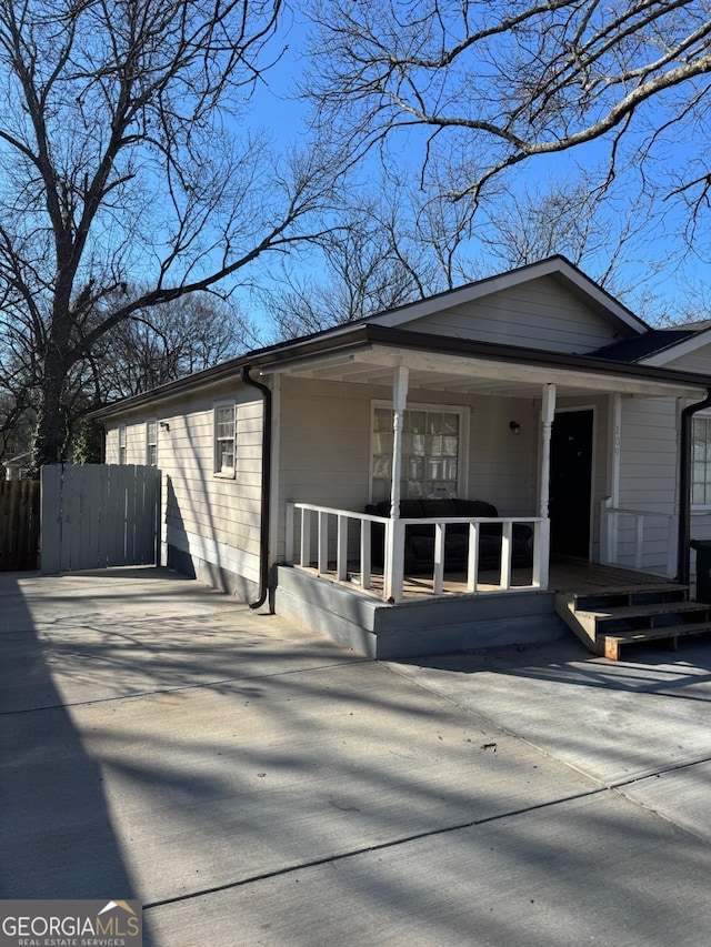 view of front of property with a porch, driveway, and fence