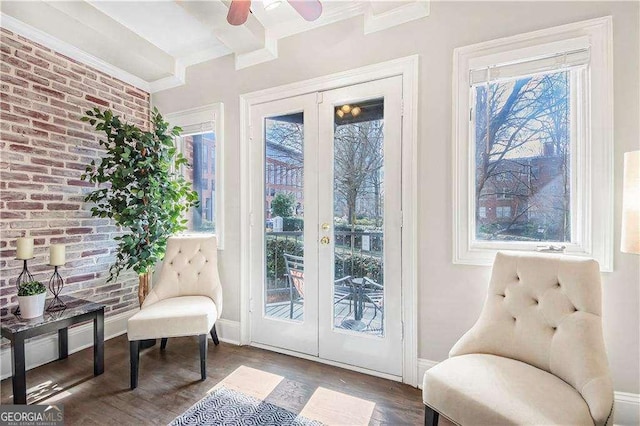 living area featuring wood finished floors, baseboards, brick wall, beam ceiling, and french doors