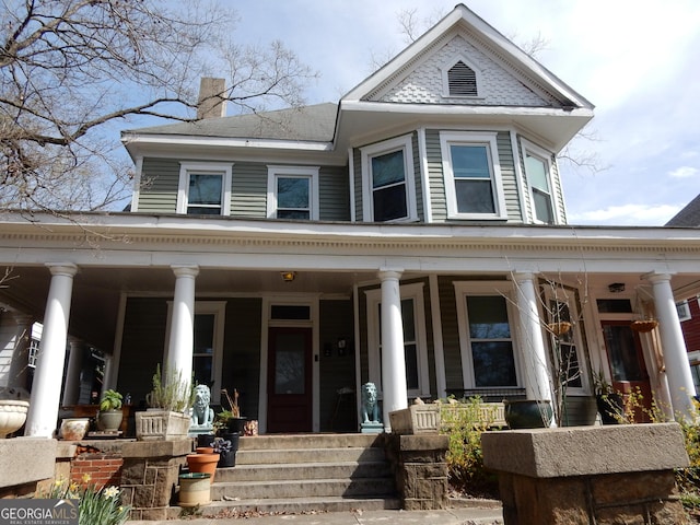 victorian home featuring covered porch and a chimney