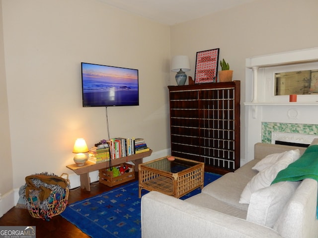 living area featuring a tiled fireplace, wood finished floors, and baseboards