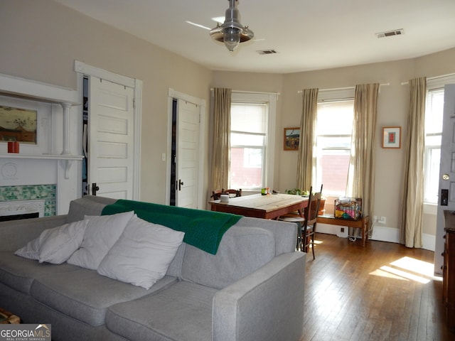 living area with visible vents, a tile fireplace, baseboards, and wood-type flooring