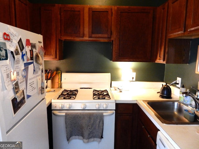 kitchen with white appliances, light countertops, and a sink