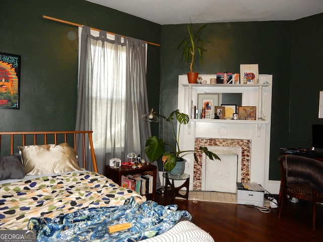 bedroom featuring a fireplace and wood finished floors