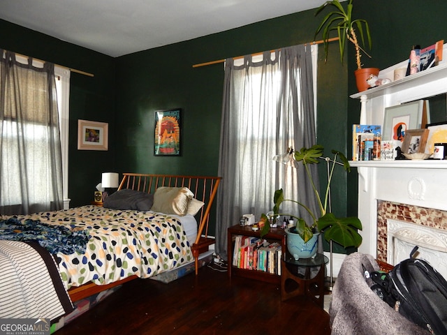 bedroom with wood finished floors and a fireplace