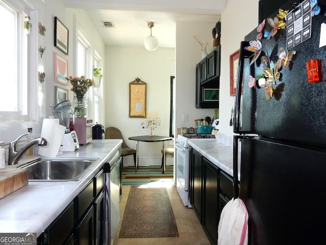 kitchen featuring visible vents, freestanding refrigerator, a sink, white gas range, and a wealth of natural light