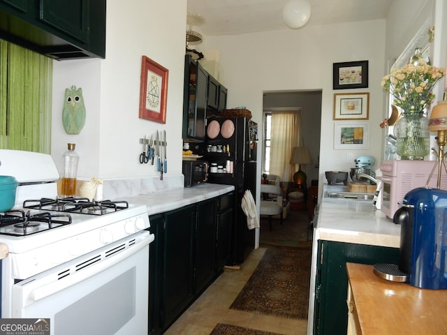 kitchen featuring light tile patterned flooring, a sink, black appliances, light countertops, and dark cabinets