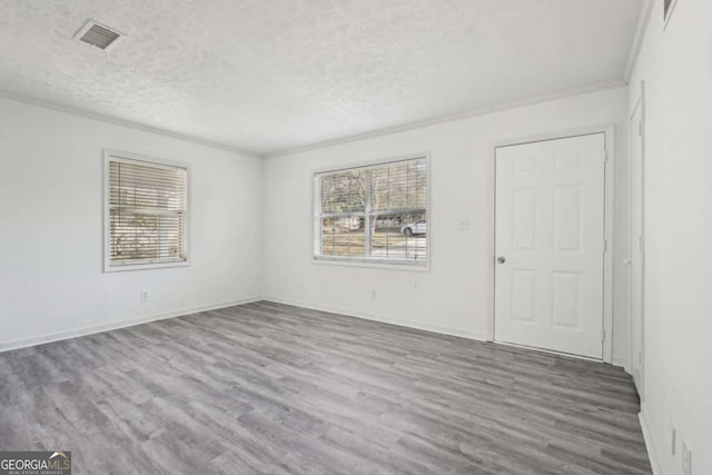 unfurnished room with a wealth of natural light, visible vents, and wood finished floors