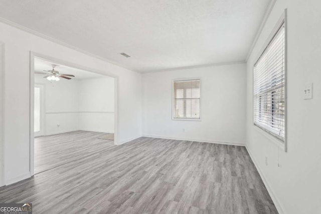 unfurnished room with visible vents, baseboards, wood finished floors, and crown molding