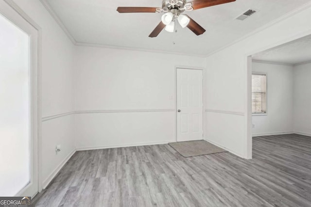 empty room with visible vents, crown molding, baseboards, and wood finished floors