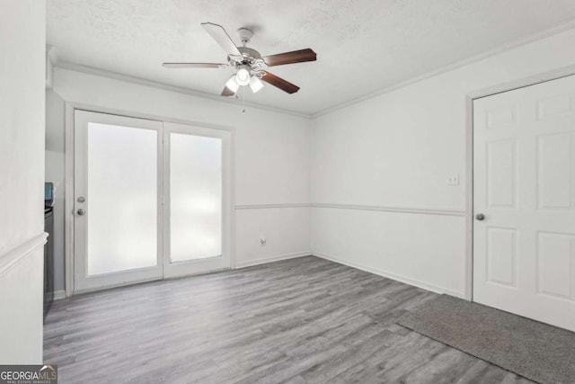 unfurnished room with a ceiling fan, a textured ceiling, wood finished floors, crown molding, and baseboards