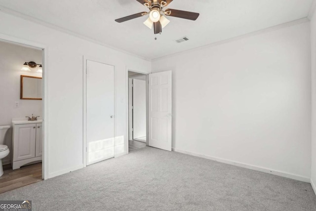 unfurnished bedroom featuring crown molding, visible vents, ensuite bathroom, and light carpet