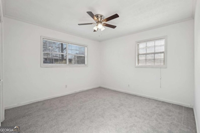 carpeted spare room featuring a ceiling fan, crown molding, and baseboards